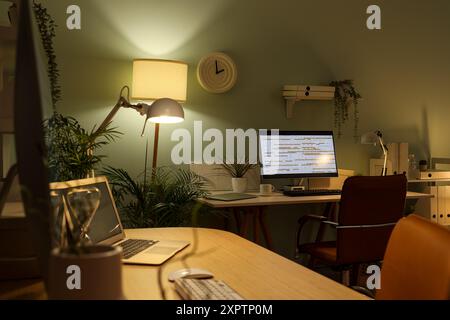 Stylish workplaces of programmer with modern computers and glowing lamps in office Stock Photo