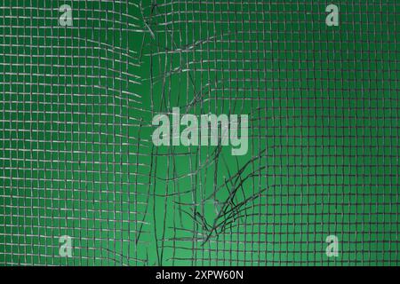 Torn window screen against green background, closeup Stock Photo