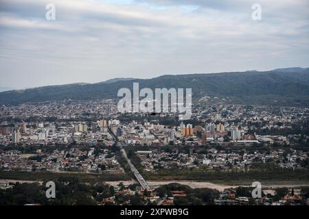 Drone flying over the city. You can see the drone, buildings, mountains, trees, clouds, sky Stock Photo