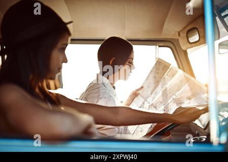 Women, friends and drive on minivan with map for direction, route and navigate on road trip in Brazil. People, tourist and location or destination for Stock Photo