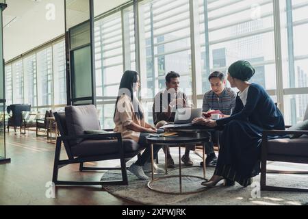Diverse Asian business executives including a disabled man in wheelchair having a casual meeting Stock Photo