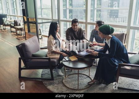 Diverse Asian business executives including a disabled man in wheelchair having a casual meeting Stock Photo