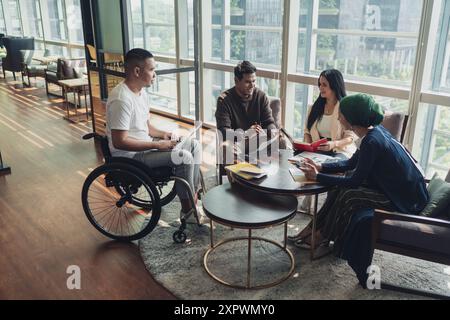 Diverse Asian business executives including a disabled man in wheelchair having a casual meeting Stock Photo