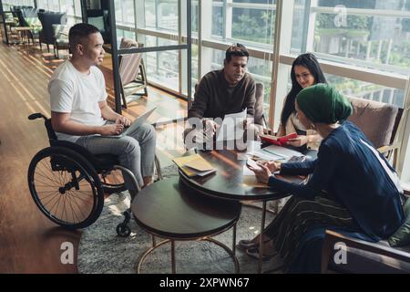 Diverse Asian business executives including a disabled man in wheelchair having a casual meeting Stock Photo