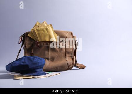 Brown postman's bag, envelopes, newspapers and hat on grey background. Space for text Stock Photo