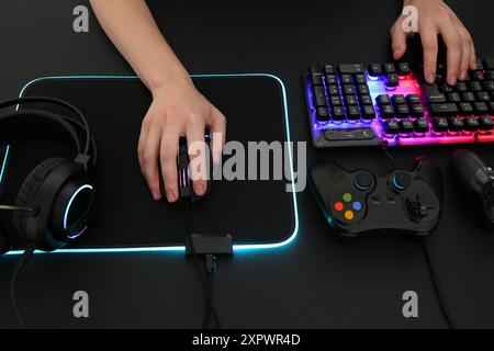 Gamer using modern wired computer mouse at dark table, above view Stock Photo