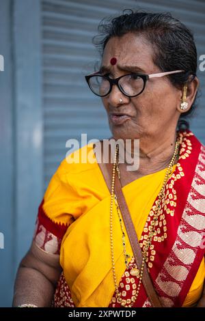 Indian Old Aged Lady wearing yellow Saree. South Asian Hindu religious elderly woman in traditional dress sari. Street photo, travel photo-Goa India-J Stock Photo