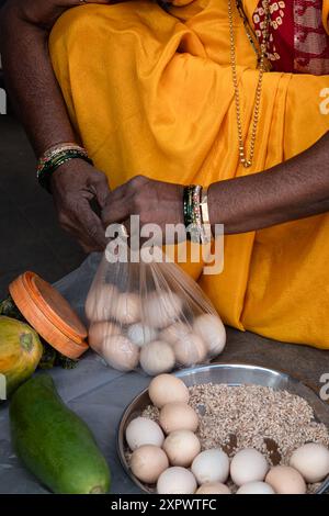 Indian woman selling farm local eggs on market or bazaar. Women selling country chicken eggs in Goa India. Close up, street photo Stock Photo