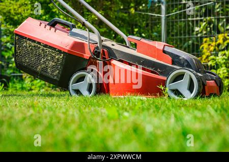 Lawn mower on green grass in small garden, gardening concept Stock Photo