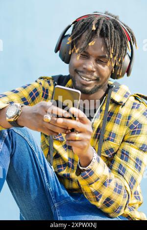black man with a headphones writing on his phone Stock Photo