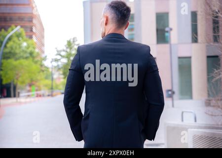 Rear view businessman walking outdoors. Stock Photo