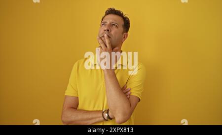 Middle-aged hispanic man pondering over isolated yellow background Stock Photo