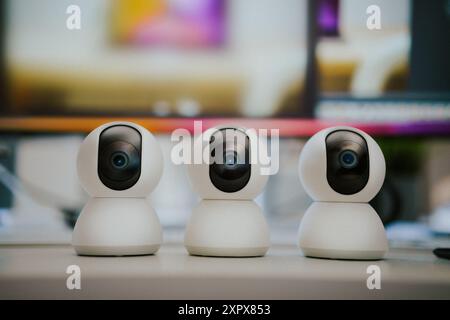 Webcam security camera. Smart home monitoring equipment on home office table. Monitors display background. Stock Photo
