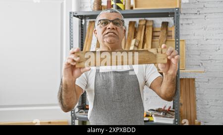 Mature man examining wood in a bright carpentry workshop Stock Photo