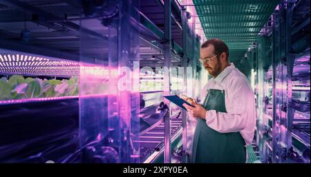 Agricultural Scientist Standing in a Corridor in a Vertical Farm Facility Next to Rack with Freshly Grown Plants. Hydroponics Technician Using Tablet Computer, Studying and Cultivating Crops Stock Photo