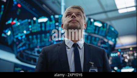 Portrait of a Handsome Adult Stock Exchange Broker Working in the Hall, Monitoring Real-Time Stocks Data, Analyzing Commodities and Exchange Market Charts. Professional Investment Agent in Office Stock Photo