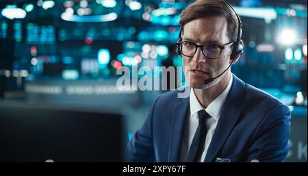 Close Up Portrait of a Smart and Thoughtful Stock Exchange Broker. Adult Man in Glasses Looking at Computer Screen, Communicating with a Client on a Phone Call, Talking About Investing Strategy Stock Photo