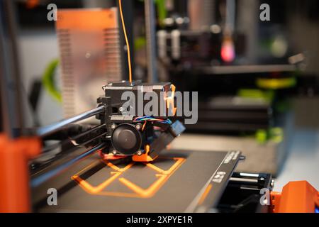 Home studio. 3D printers at work. Production, passion and hobby. Orange plactic filament. Stock Photo