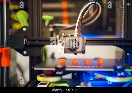 3d printer with printed orange parts. Home lab background Stock Photo