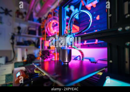3D printer with a printed object on the table. The interior of a home workshop. Wall with tools in the background. Colorful backlight Stock Photo