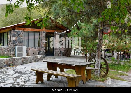 A wooden table sits outside a stone cottage in a tranquil setting. Stock Photo