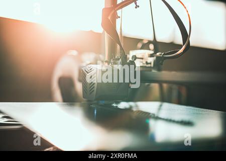 Close-up of a 3D printer head working in the rays of the setting sun. 3D printing technology in dynamic lighting, perfect for illustrating modern manu Stock Photo