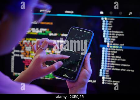 Examining Code on Smartphone While Sitting at Desk Stock Photo