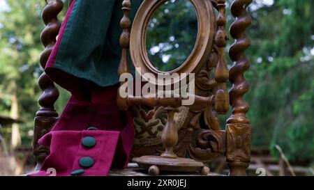A knights chair in the garden, an old mirror, a dress. Stock Photo