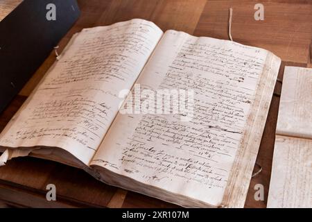 An open vintage manuscript with handwritten text on aged paper, resting on a wooden desk. Stock Photo