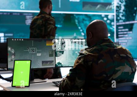 Army IT expert in control center collecting real time battlefield data, process satellite surveillance imagery for successful military defense mission. Using green screen isolated display. Stock Photo