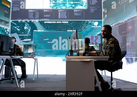 Army intelligence expert utilize advanced computer systems and satellite data to protect national security, support and maintain operational efficiency in a high tech command center military base. Stock Photo