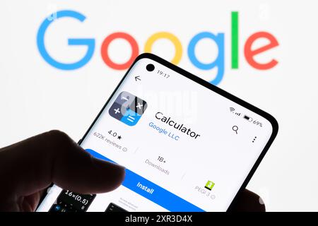 Close-up of a smartphone screen displaying Calculator app with Google logo in the background, highlighting the connection between Calculator and Googl Stock Photo