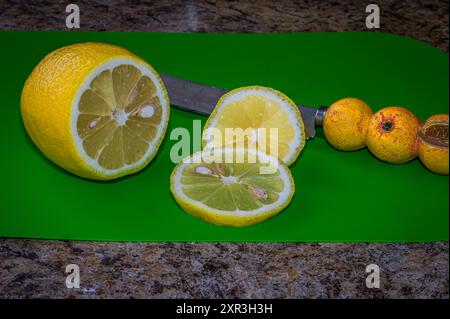 Fresh juicy sliced lemon on a green cutting board. on the kitchen counter Stock Photo