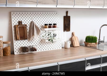 Interior of stylish kitchen with black counters, peg boards and white ...