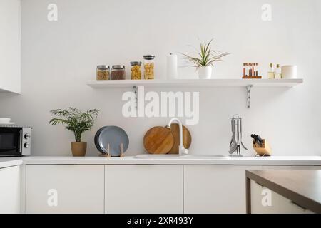 Stack of clean plates near sink on white counter in kitchen Stock Photo