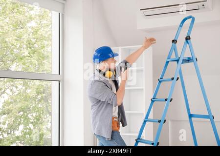 Male contractor talking on radio transmitter near stepladder in room Stock Photo