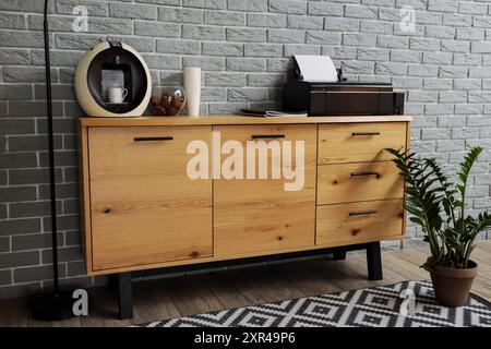 Modern printer and coffee machine on commode near grey brick wall in office Stock Photo