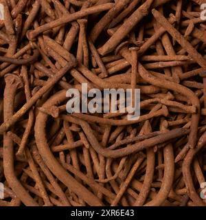close-up of rusty old warped nails in full frame background, corroded and unusable brownish steel construction fastening material result of rust, bent Stock Photo