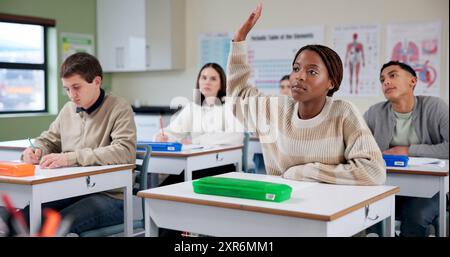 Girl, education or class in high school for question, lesson or biology lecture. Student, writing or hand raised at desk for learning, asking or Stock Photo