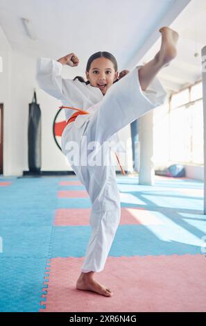 Martial arts, kick and girl in studio for fitness, training and fight with orange belt, development and energy. Student, kung fu and portrait in dojo Stock Photo