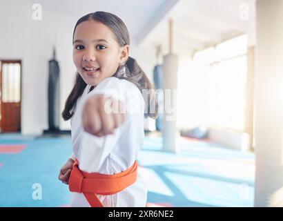 Martial arts, fist and girl in studio for fitness, training and fight with orange belt, development and energy. Student, kung fu and practice in dojo Stock Photo