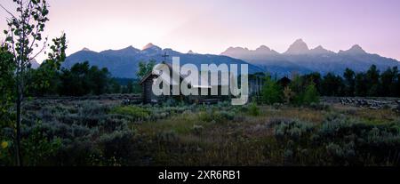 Chapel of the Transfiguration in Grand Teton National Park at sunset, Teton Mountain Range in the background, Tree in foreground Stock Photo