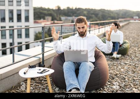 Young professionals working remotely on rooftop with laptops Stock Photo