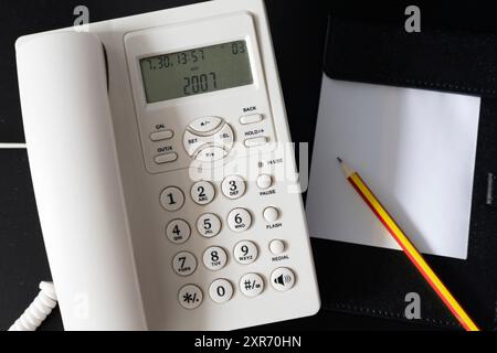 Office Desk Essentials: A Phone, Notepad, Pencil, and Keyboard on a Workspace, Featuring Digital Communication Tools and Stationery for Efficient Note Stock Photo