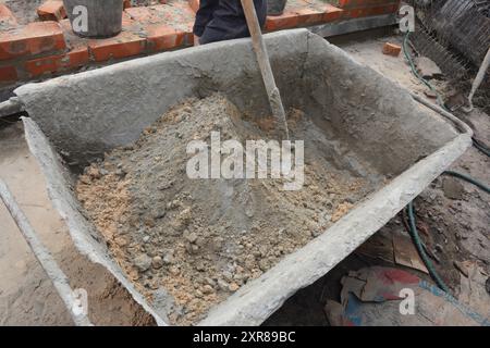 Construction workers prepare concrete mixing sand and cement Stock Photo