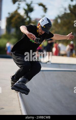 Inline skater grinding on a coping rail in a concrete skate pool at ...