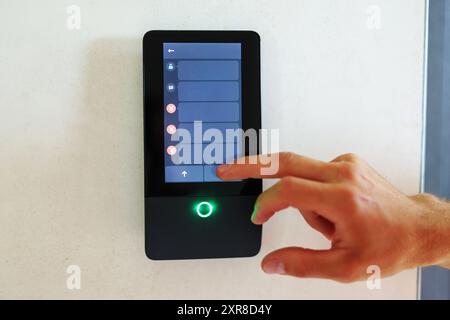 Intercom communication control panel with home automation function and feature hang on wall in apartment room. Stock Photo