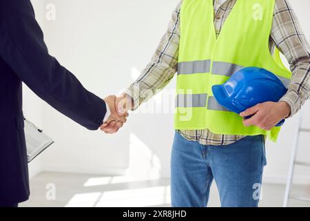 Foreman making deal with architect shaking hands standing in empty room at construction site Stock Photo