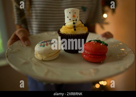 Snowman cupcake and holiday macarons on white plate Stock Photo
