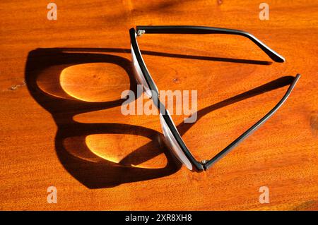 reading glasses shadow on wooden table top Stock Photo